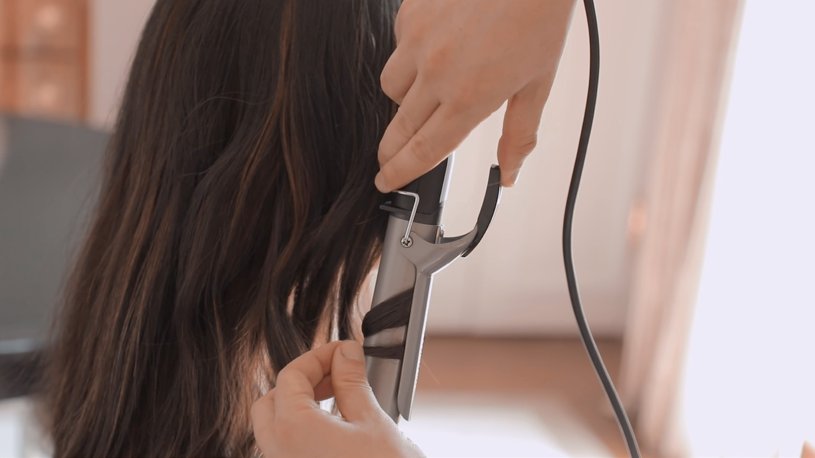 Mujer aplicando aceite para el cabello en la rutina diaria, mostrando un cabello brillante y suave.
